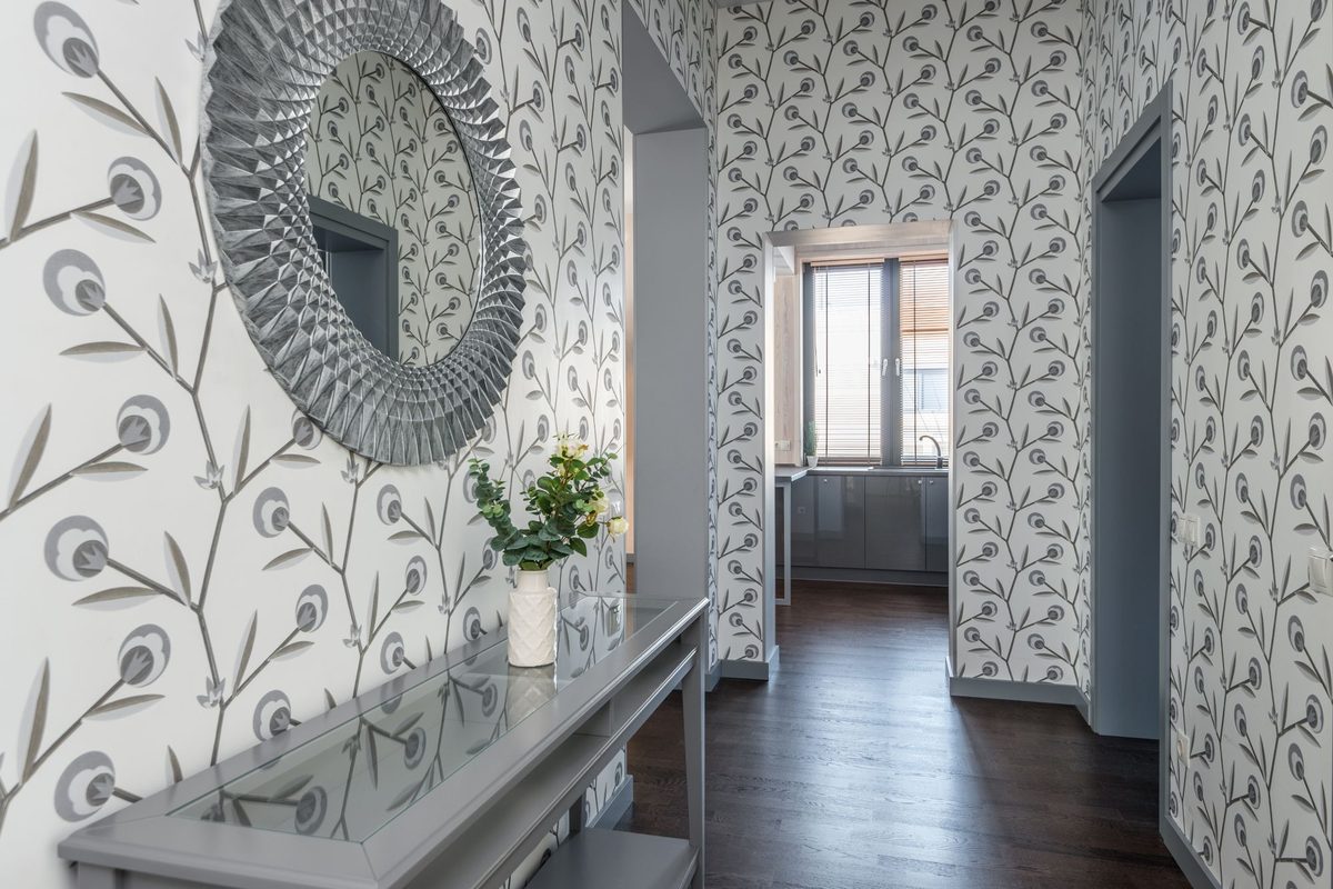 Entryway with peacock-motif botanical wallpaper and a round mirror above a slim console