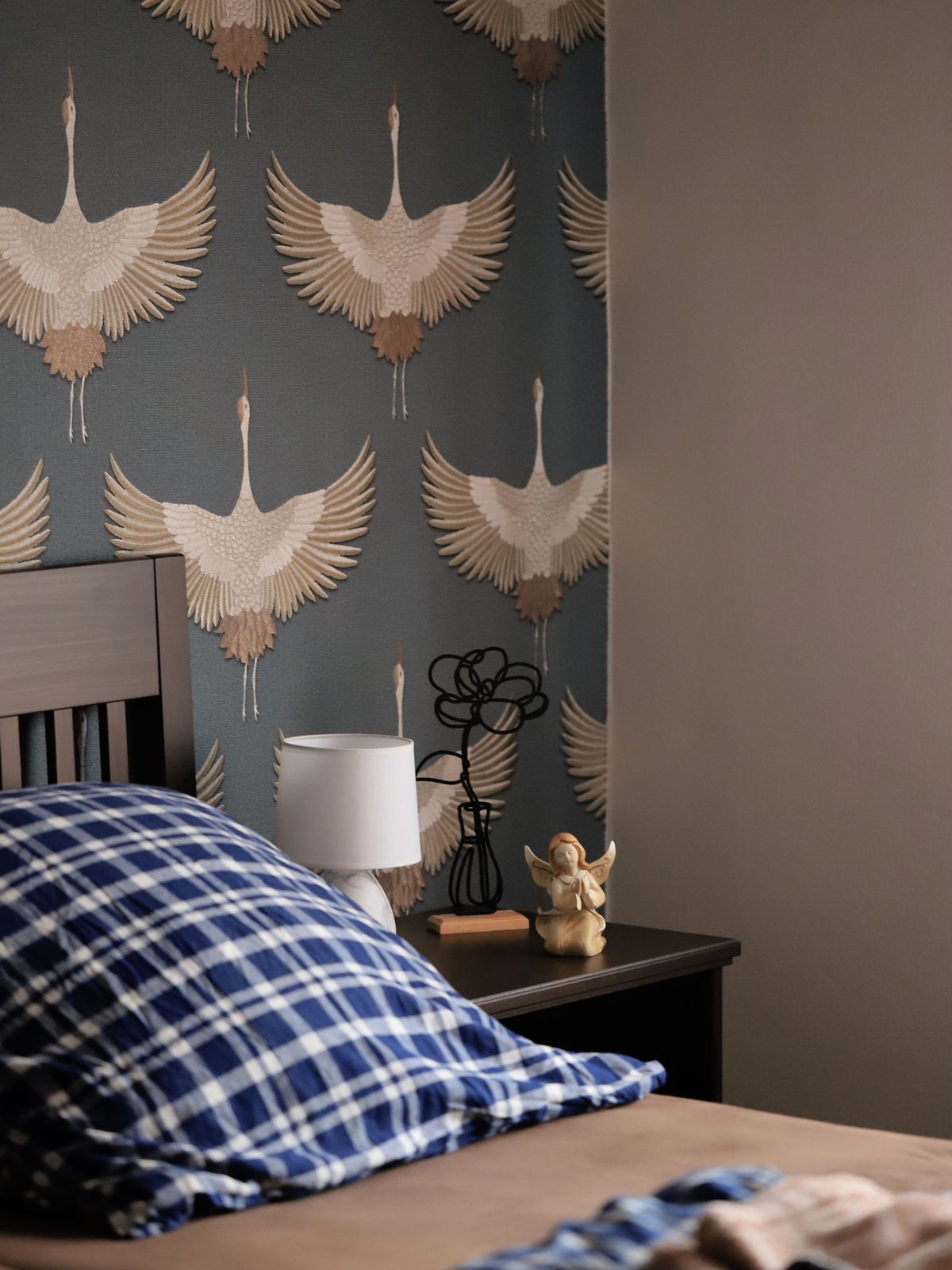 Bedroom with soft grey botanical crane-pattern wallpaper behind the bed