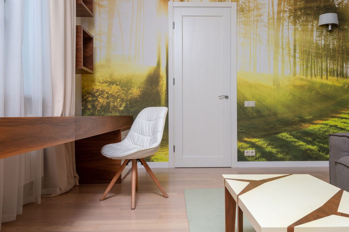 Home office with a scenic forest-mural wallpaper and a wooden writing desk