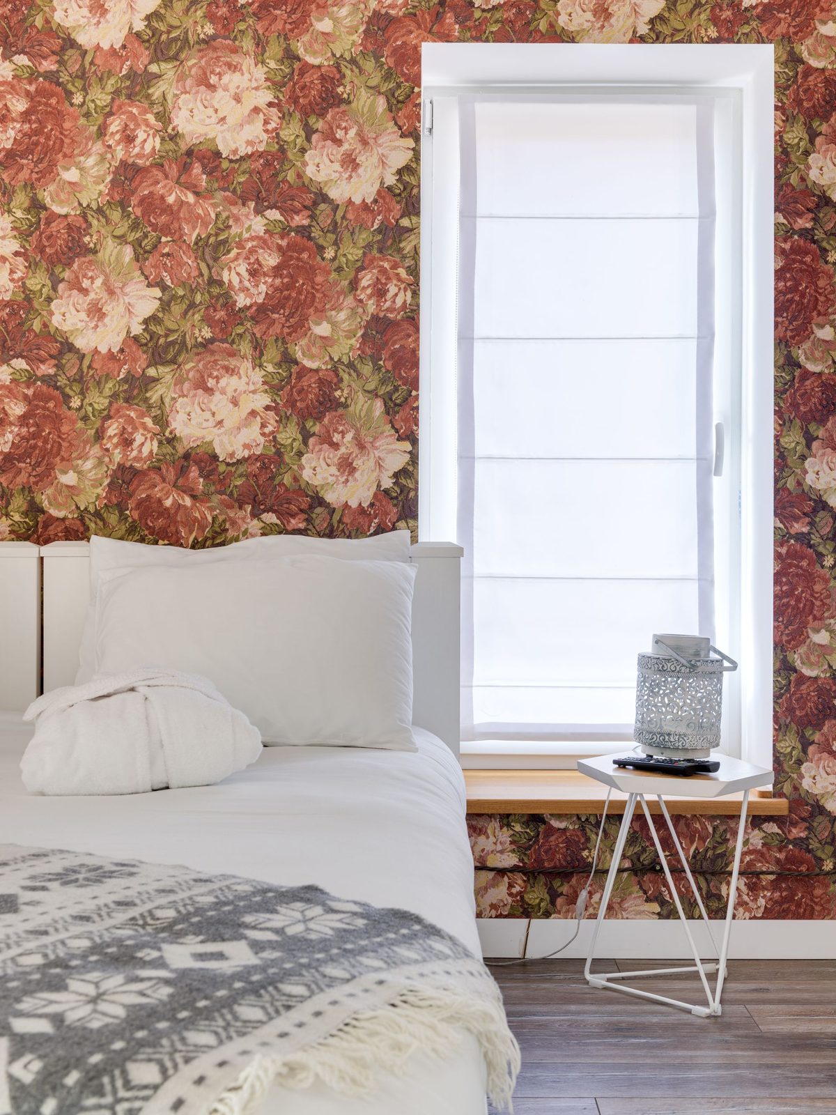 Bedroom with vintage red floral wallpaper beside a bright window
